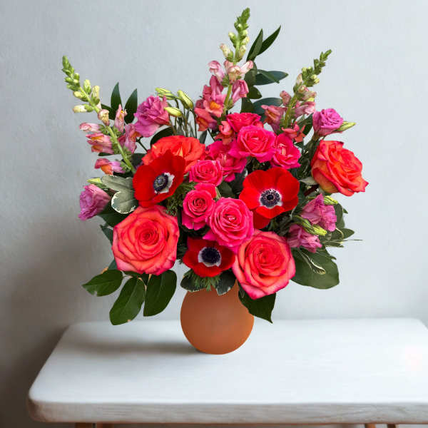 Pink and red mixed bouquet in a round orange vase