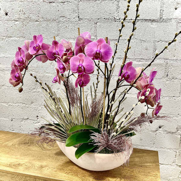 Pink orchid arrangement in a white oval bowl