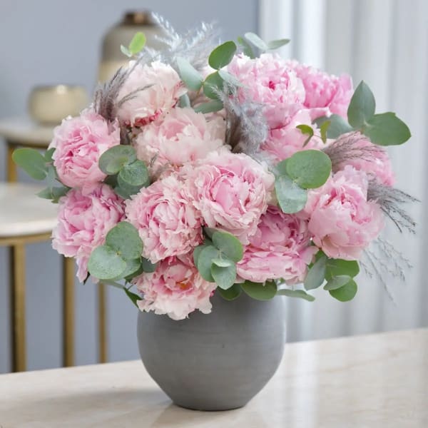 Pink peonies arranged in a gray vase with eucalyptus