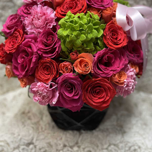 Bouquet of pink, red, and orange roses with a green hydrangea center