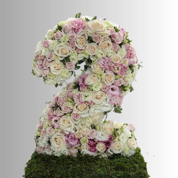 Floral arrangement shaped like the number 2 with pastel roses on a moss base