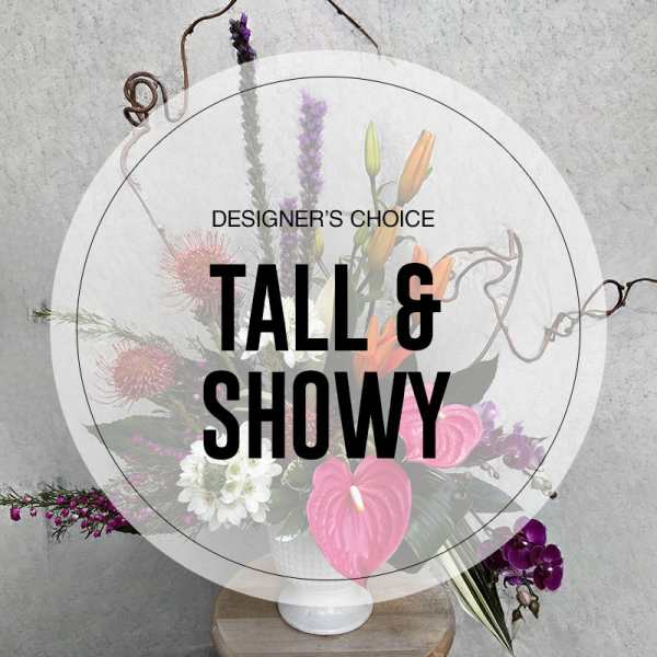 Tall floral arrangement in a white vase with pink and purple blooms