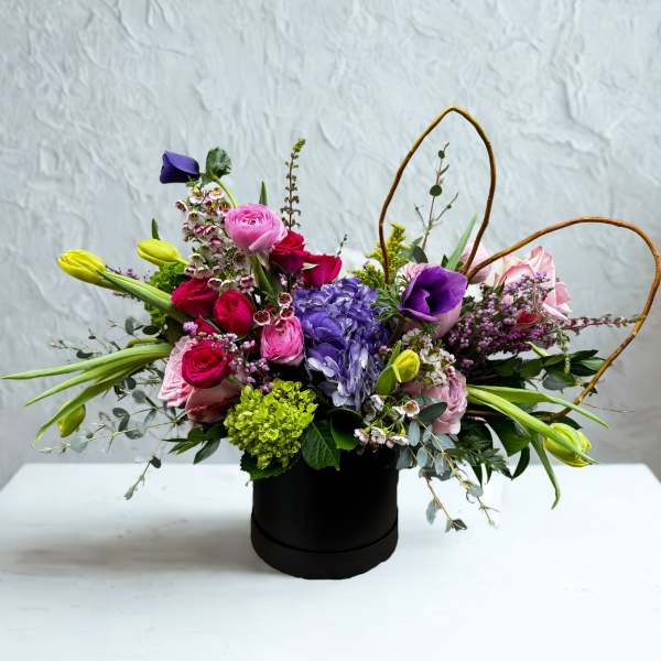 Mixed bouquet in a black hatbox with pink, purple, and yellow flowers