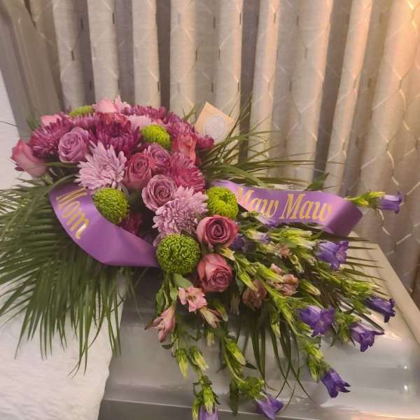 Purple and pink floral casket spray with ribbon