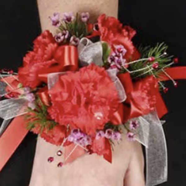 Red floral wrist corsage with ribbons on a person's wrist