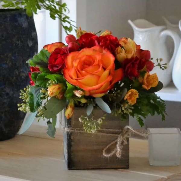 Orange and red rose arrangement in a wooden box