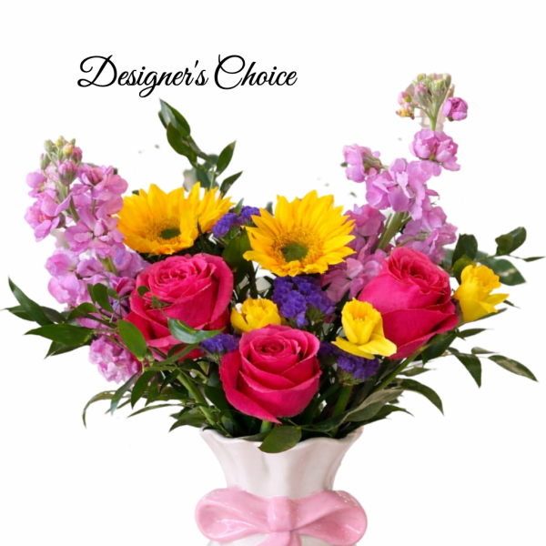 Bright mixed bouquet with pink roses, yellow sunflowers and purple blooms in a white vase with pink bow
