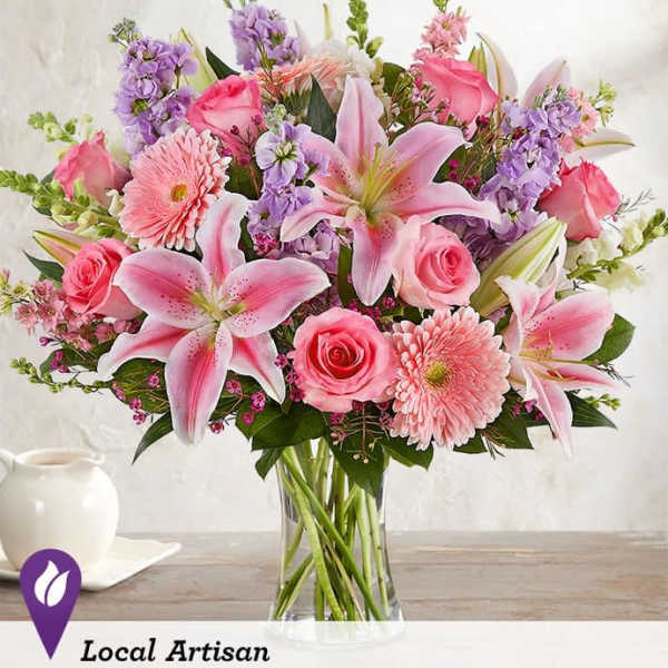 Pink lilies, roses, and gerbera daisies in a clear glass vase