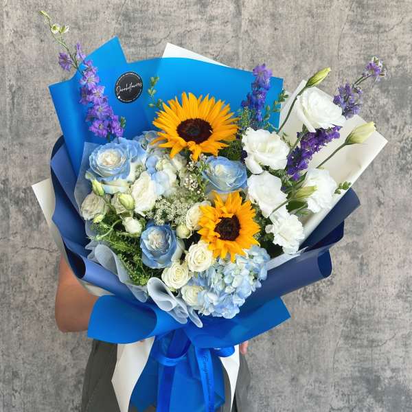 Bouquet of blue and white flowers with sunflowers wrapped in blue paper