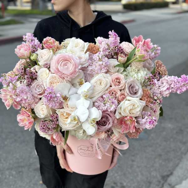 Large pastel bouquet of roses, tulips, and orchids in a pink hatbox