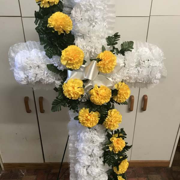White floral cross with yellow flowers on an easel