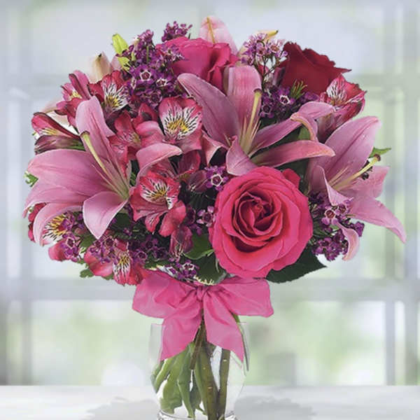 Pink and purple bouquet of lilies, roses, and alstroemeria in a glass vase