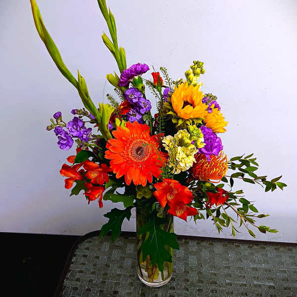 Colorful mixed bouquet in a clear glass vase with tall green spikes