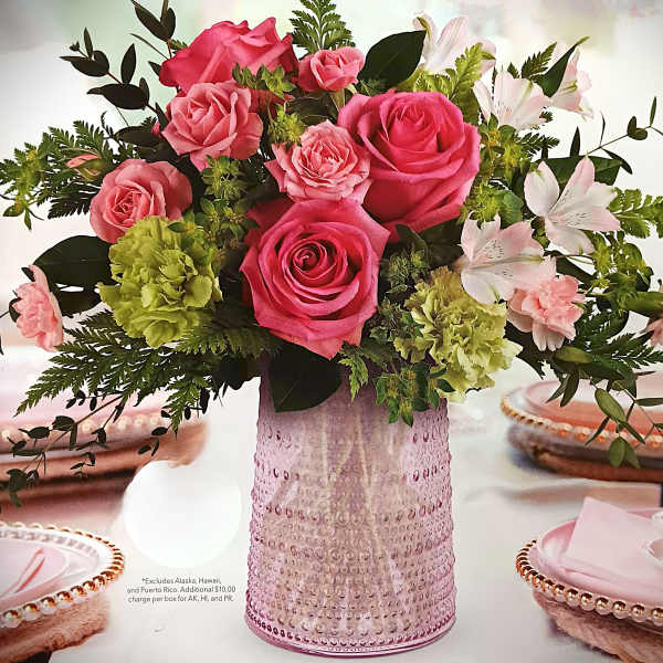 Pink roses and pale flowers arranged in a textured pink vase