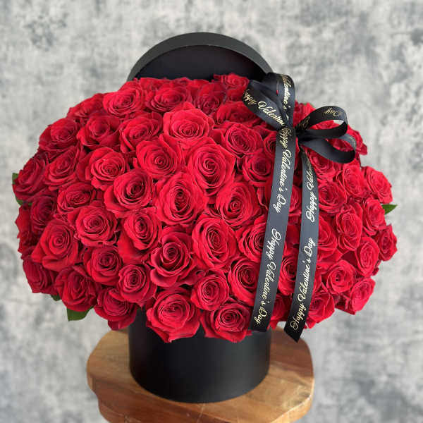 Large bouquet of red roses in a black hat box with a ribbon