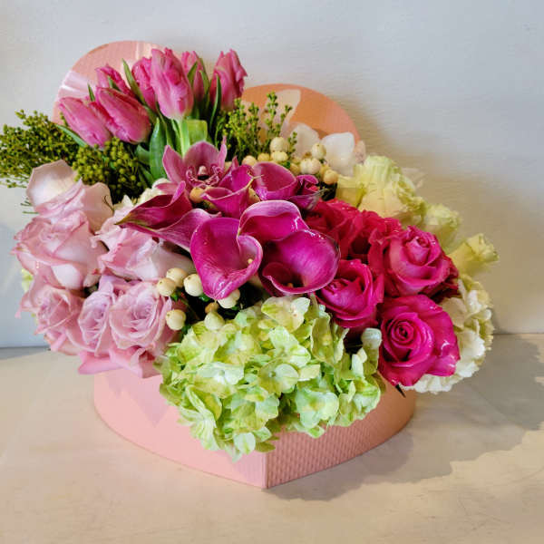 Pink and magenta floral arrangement in a pink heart-shaped box