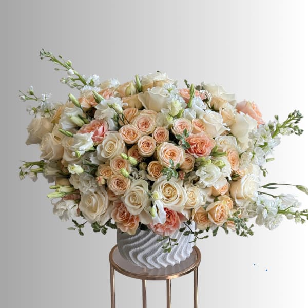 Large bouquet of cream and peach roses in a textured white vase