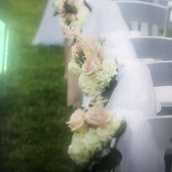 White chairs decorated with pale floral garlands and sheer fabric