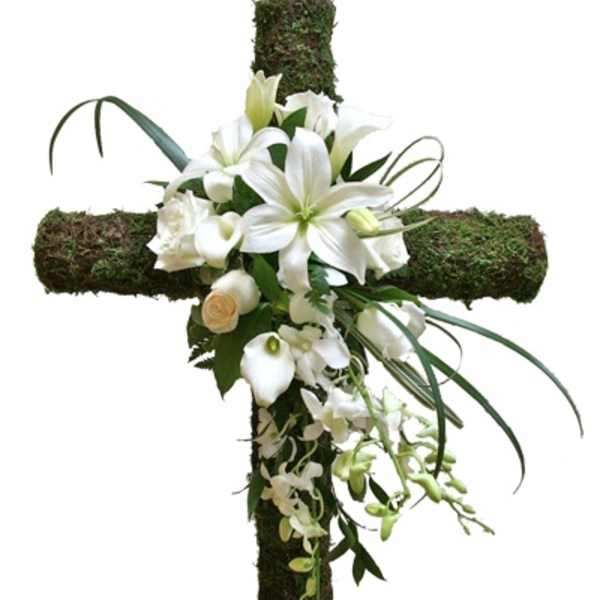 White flowers arranged on a moss-covered cross