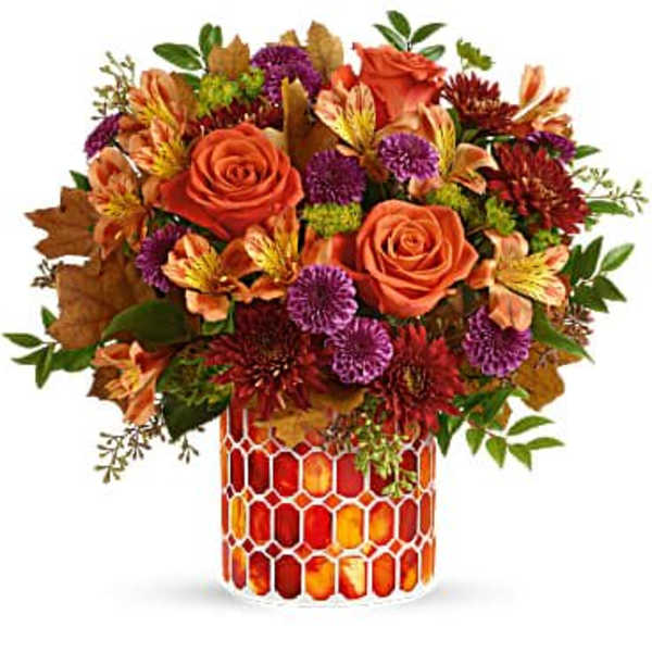 Autumn bouquet of orange roses and purple flowers in a patterned vase