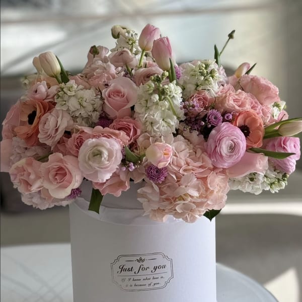 Pink and white mixed flower arrangement in a white hat box