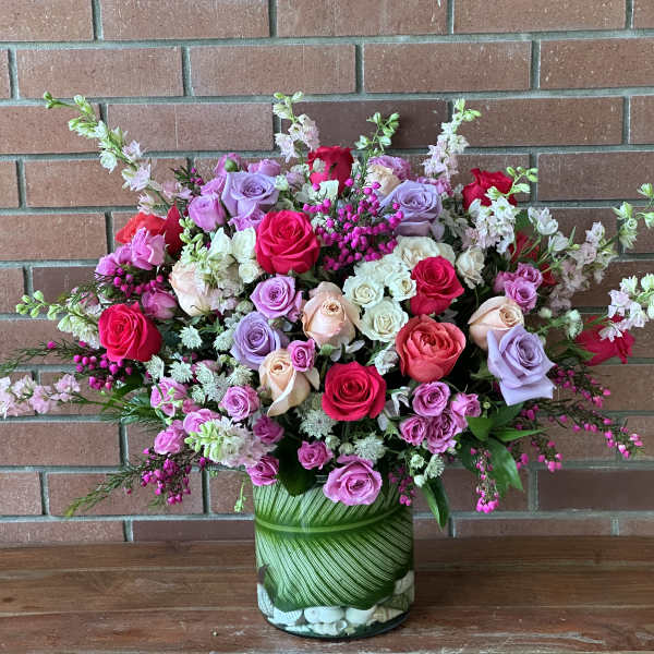 Mixed pink, lavender, and white roses in a glass vase
