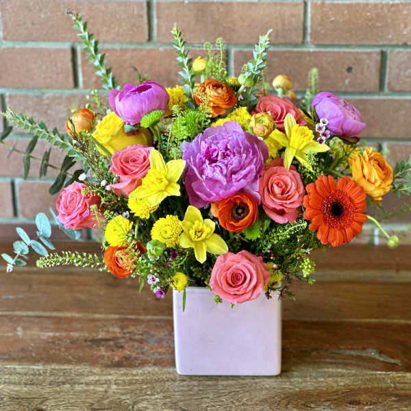 Colorful mixed bouquet in a square lavender vase