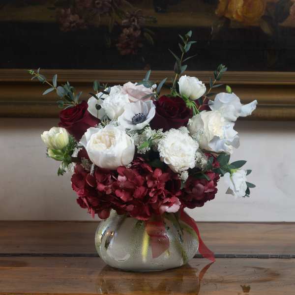 Bouquet of red and white flowers in a round glass vase