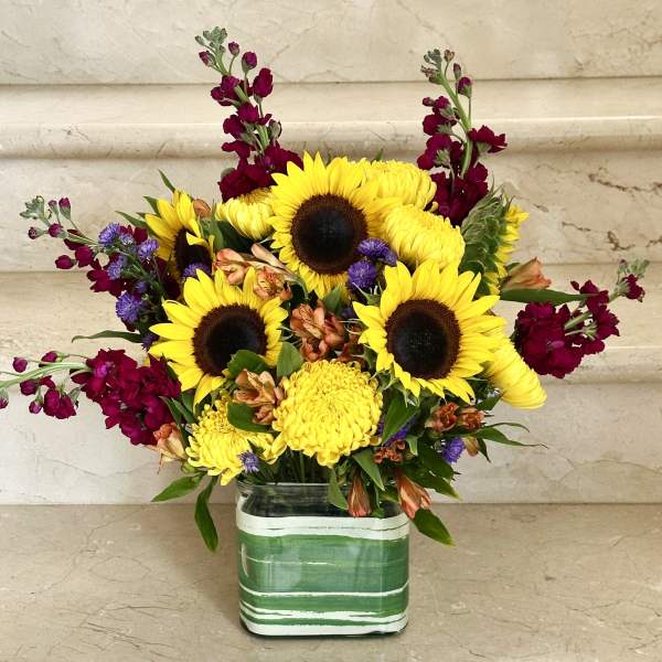 Sunflowers and mixed blooms arranged in a striped glass vase