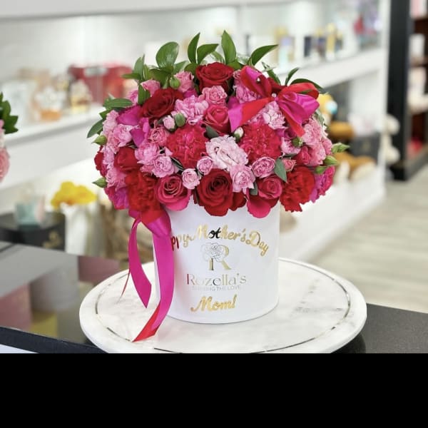 Pink and red rose arrangement in a white hat box with a ribbon