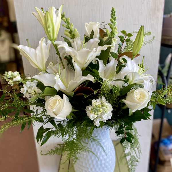 White lilies and roses arranged in a white vase
