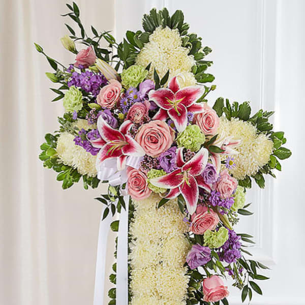 Standing floral cross with pink roses, lilies, and white mums