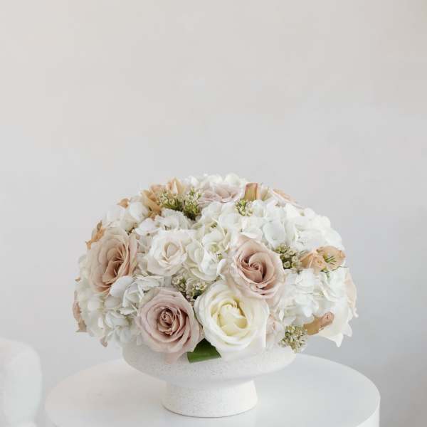 Blush and white roses with white hydrangeas in a white pedestal vase
