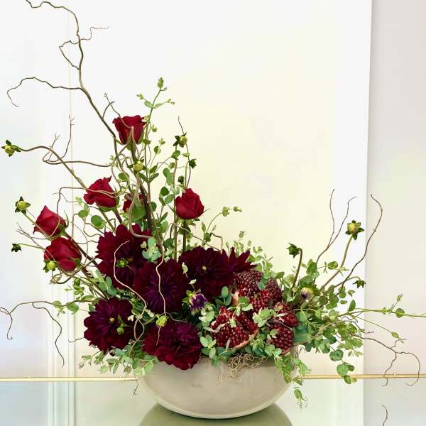 Red roses and dark burgundy dahlias in a white bowl vase