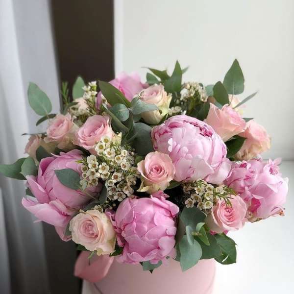 Pink peonies and roses arranged in a round pink box