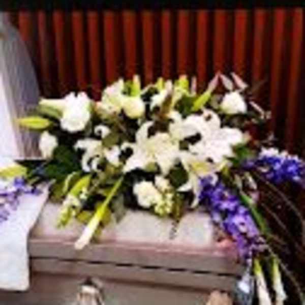 White floral arrangement with purple accents on a casket