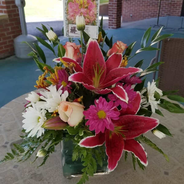 Bouquet of pink lilies, white daisies, and roses in a glass vase
