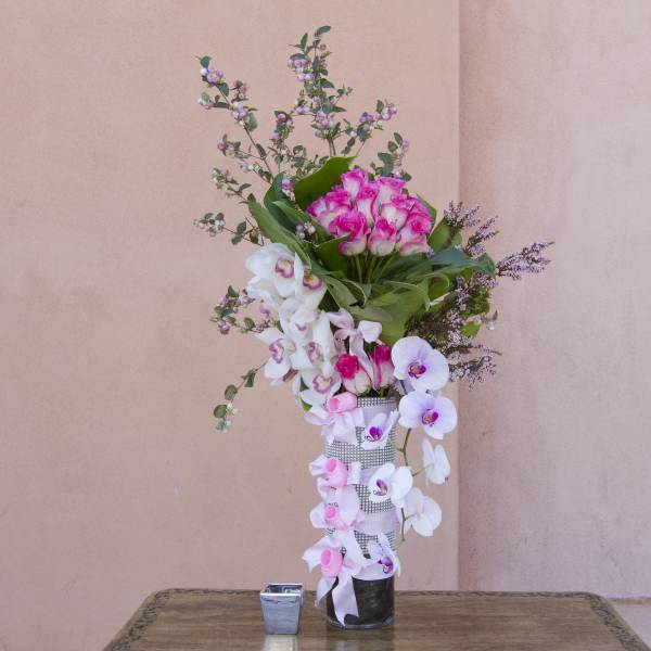 Tall pink and white orchid arrangement in a glass vase