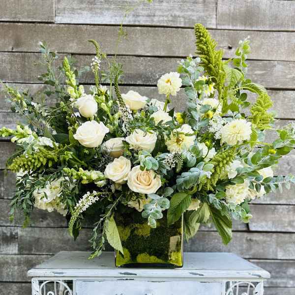 White roses and pale blooms arranged in a square glass vase