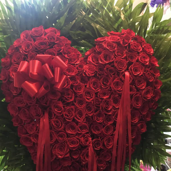 Heart-shaped red rose arrangement with ribbon accents