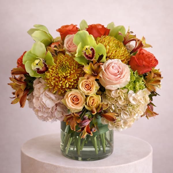 Mixed bouquet of roses, hydrangeas, orchids, and chrysanthemums in a glass vase