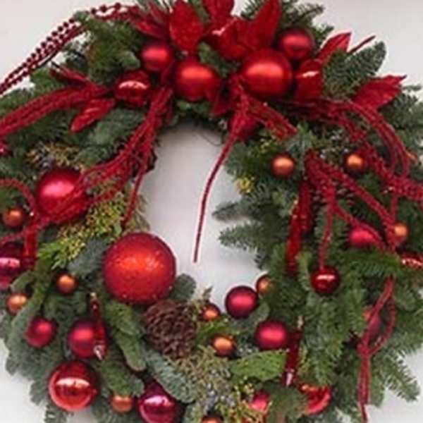Christmas wreath with red ornaments and ribbon on evergreen foliage