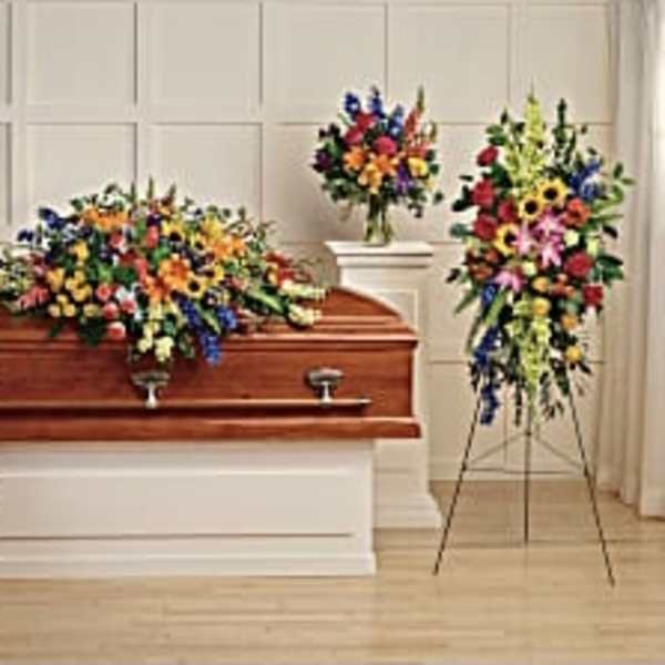 Colorful floral funeral casket spray with standing wreaths and arrangements