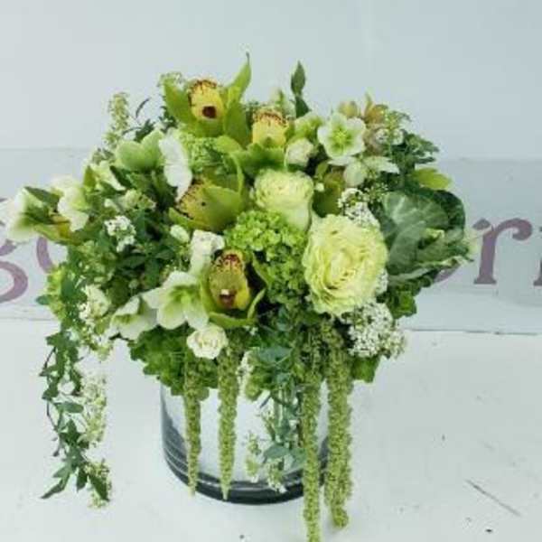 Green and white floral arrangement in a round container
