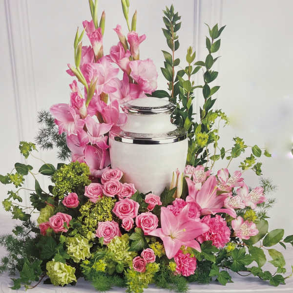 Pink floral arrangement around a white urn with silver trim