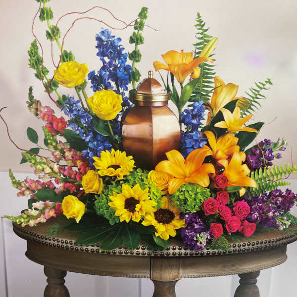 Colorful floral arrangement around a copper urn with yellow roses and lilies
