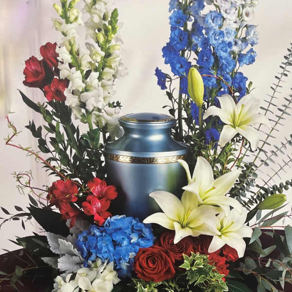 Funeral urn surrounded by red, white, and blue flowers