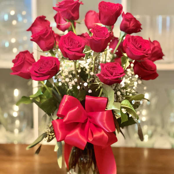 Bouquet of red roses in a glass vase with a large red ribbon