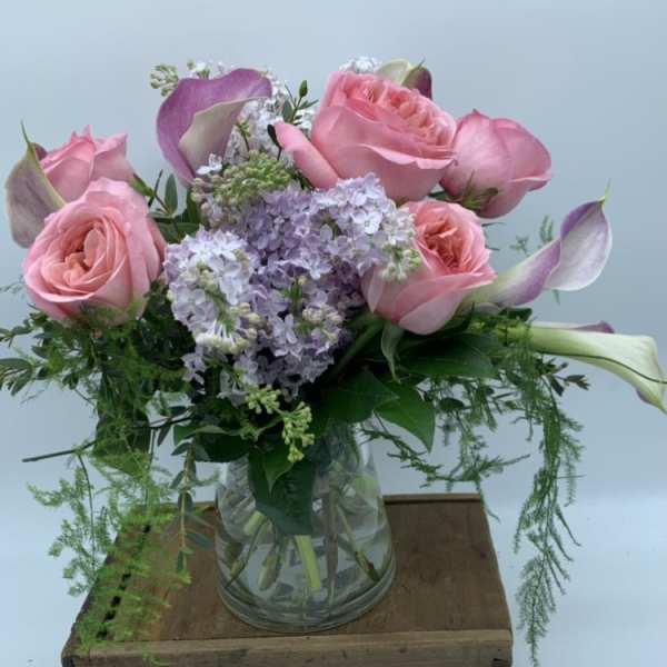 Pink roses and lavender flowers arranged in a glass vase