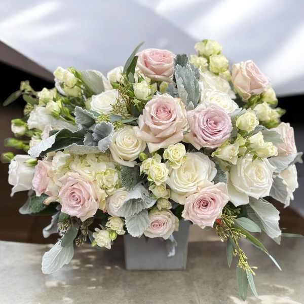 Blush and white roses arranged in a low square vase